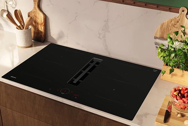 a kitchen counter with a stove top and a bowl of fruit