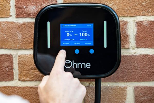 a person is touching a button on a ev device that is connected to a brick wall