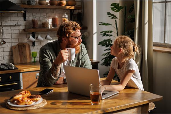 a man and a girl sitting at a table with a laptop