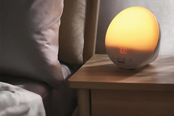 a bedside table with a lamp and a clock on it