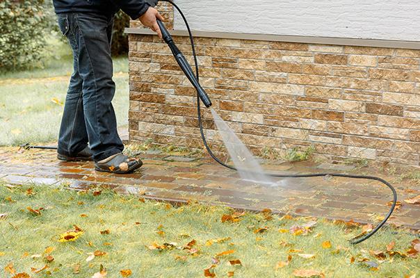 a man using a pressure washer to clean the sidewalk