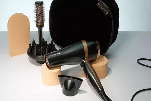 a hair dryer, brush, and comb on a table
