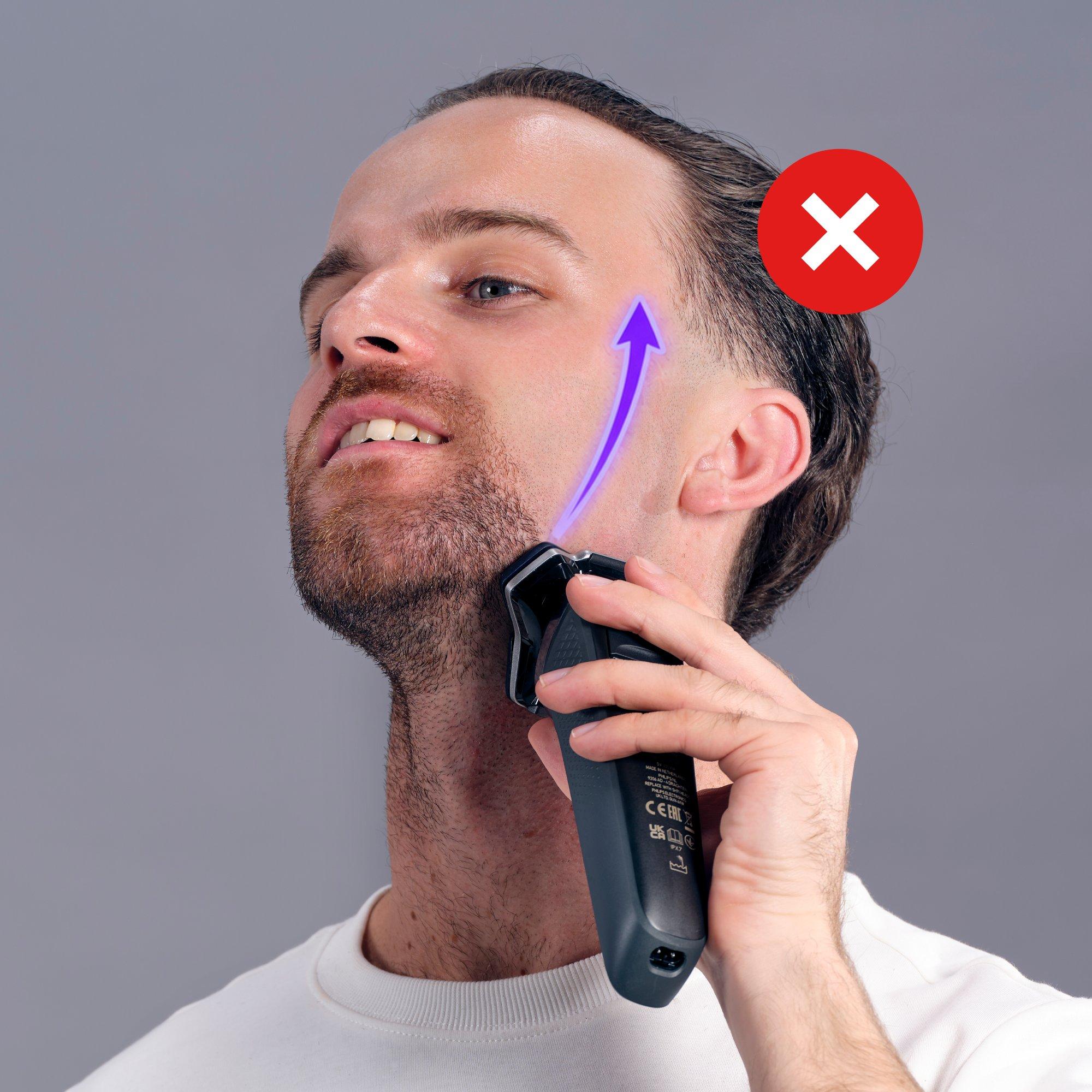 a man with a beard is using an electric shaver to trim his beard