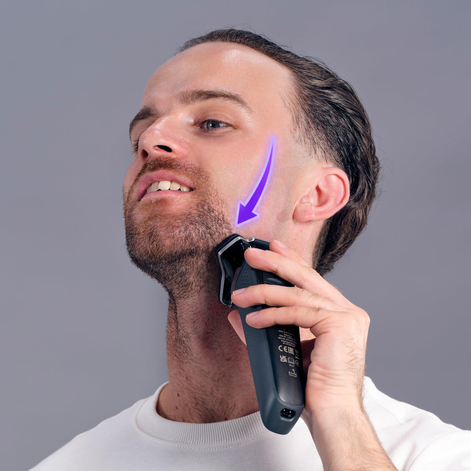 a man with a beard is shaving his face with an electric razor