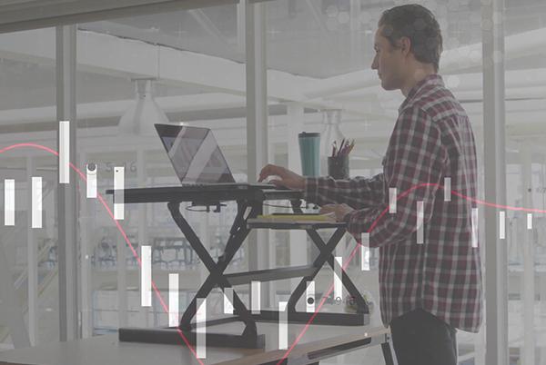 a man standing on a laptop desk with a graph on the wall