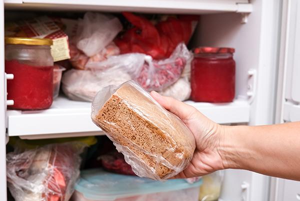 a person holding a sandwich in a refrigerator full of food