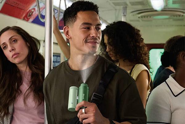 a man with a green bottle on a train with people