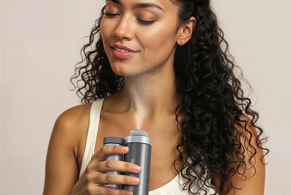 a woman with curly hair is using a device to blow air into her mouth