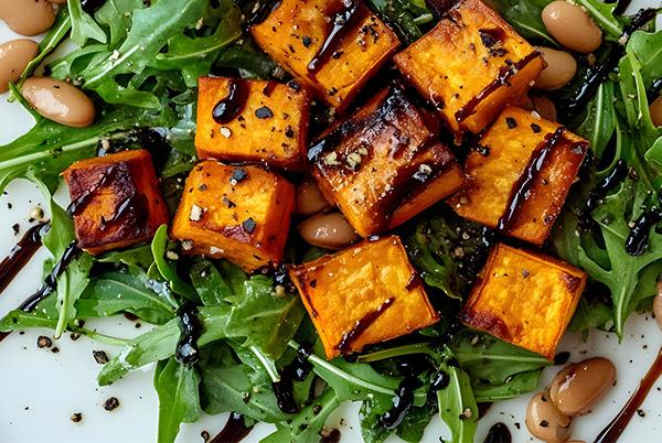 a plate of a salad with tofu and greens on it