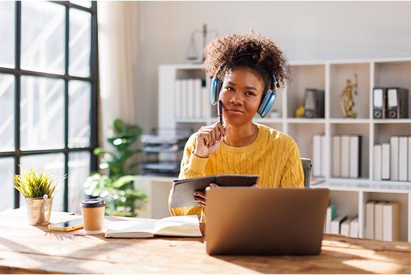 a woman with headphones on is sitting at a desk with a laptop