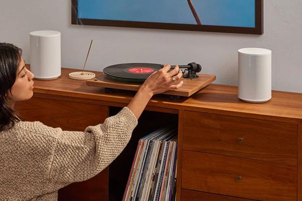 a woman playing a record on a turntable in a living room