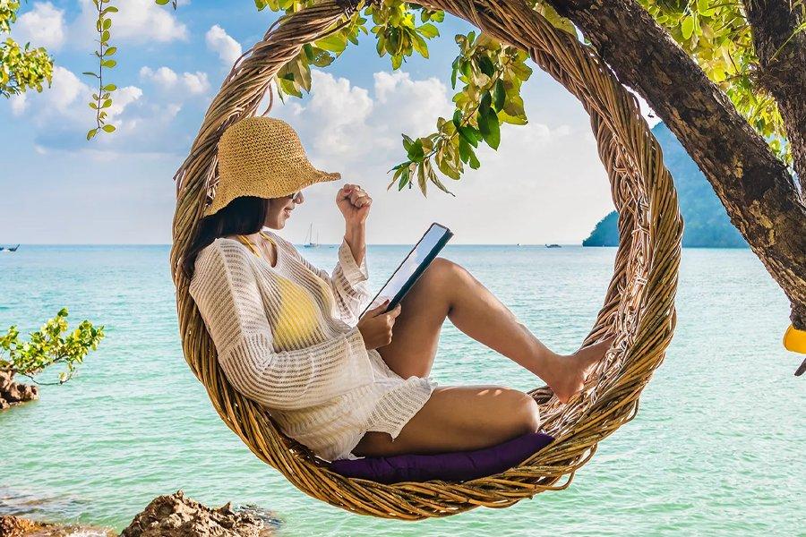 A woman sitting in a hammock in front of the sea