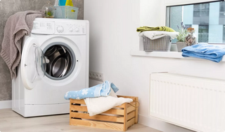 A tumble dryer in a laundry room surrounded by clothing