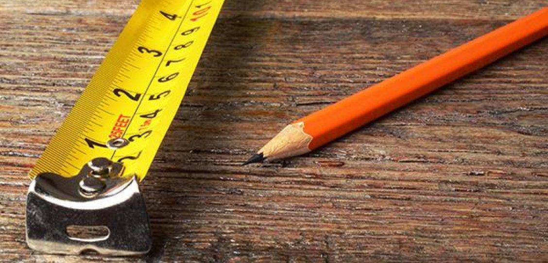 a pencil and a measuring tape on a wooden table
