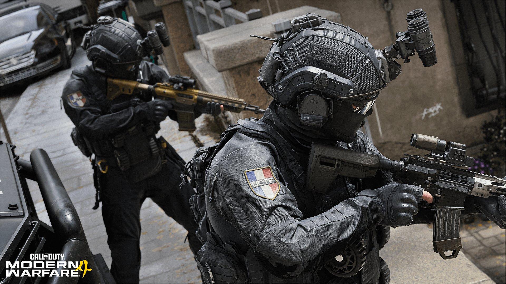 Two soldiers wearing masks and pointing their guns stand on a street
