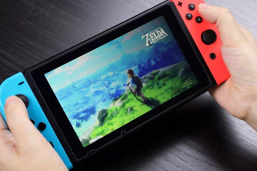 Two hands holding a Nintendo Switch with Zelda on the screen