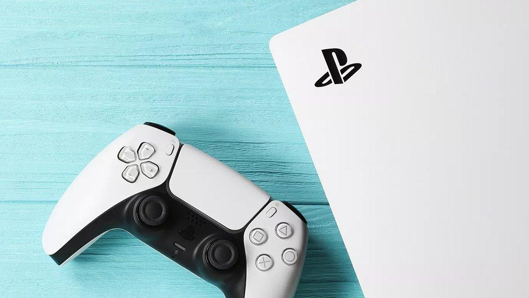 A white PlayStation 5 and controller on a blue wooden background
