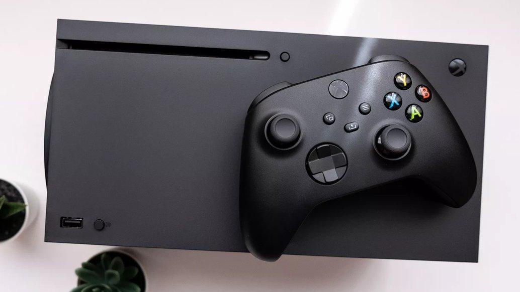 A black Xbox Series X console lying on a white background with a controller on top of it