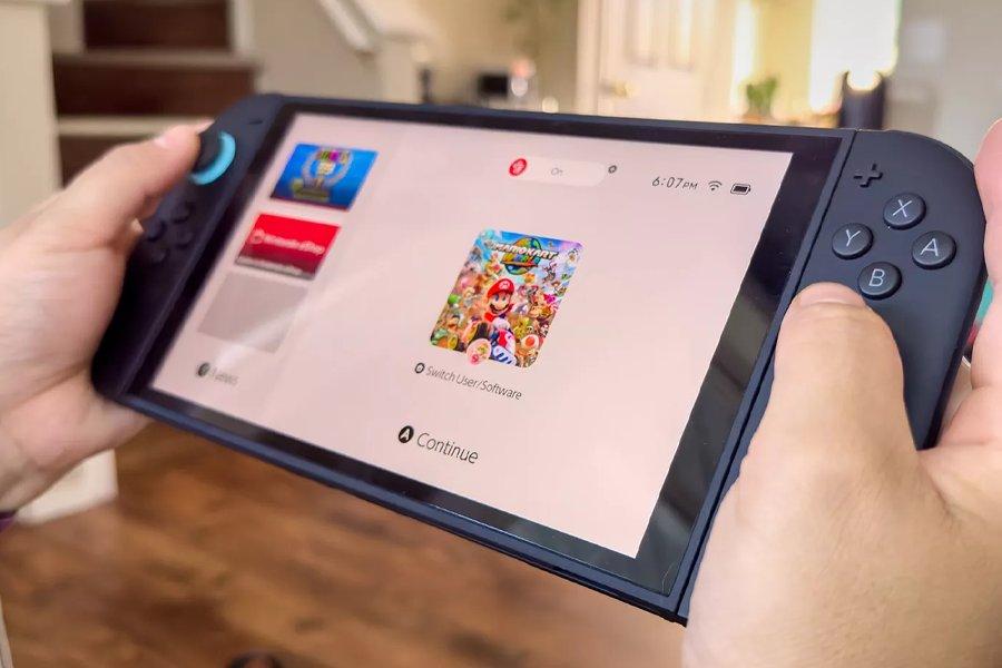 Two hands holding a Nintendo Switch 2 with Mario Kart loading on the screen
