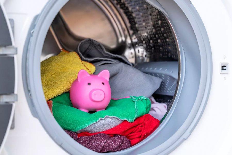 Close up of a washing machine drum with clothes and a piggybank inside