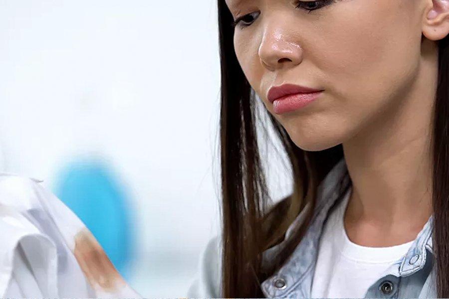 A woman looking at a stain on a shirt