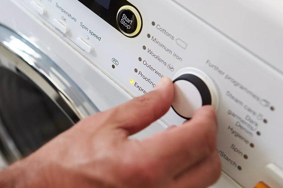 A hand changing the settings on a washing machine