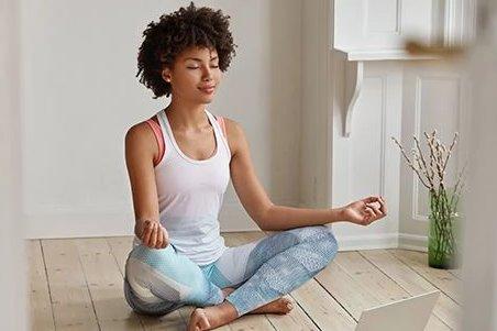 a woman sitting in a lotus position on the floor with a laptop
