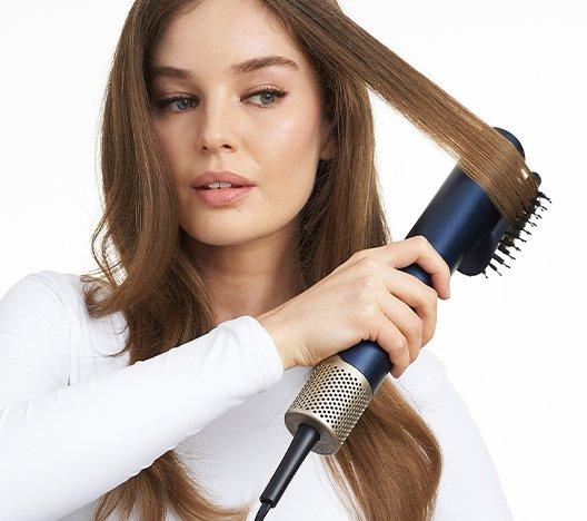 a woman styling her hair with a Babyliss Airwand
