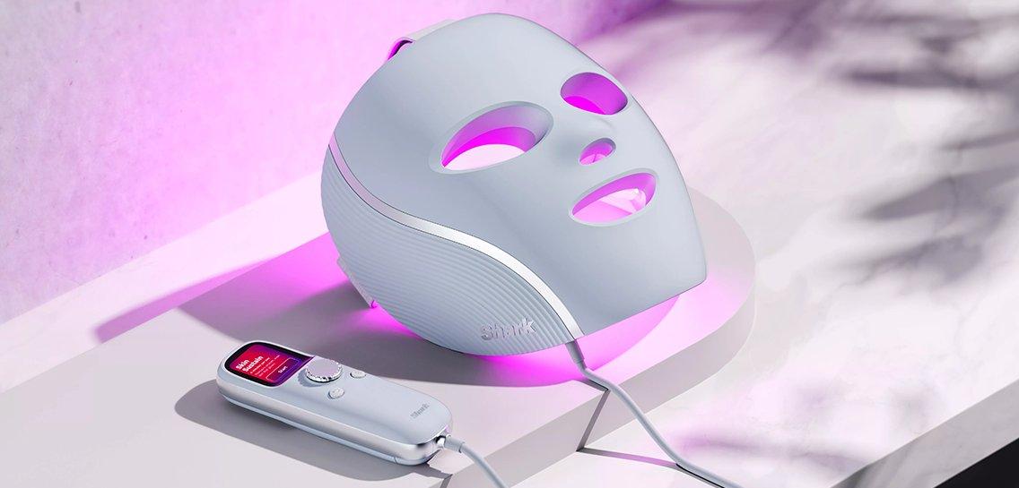 a pink beauty tool sits on a counter next to a bottle of lotion