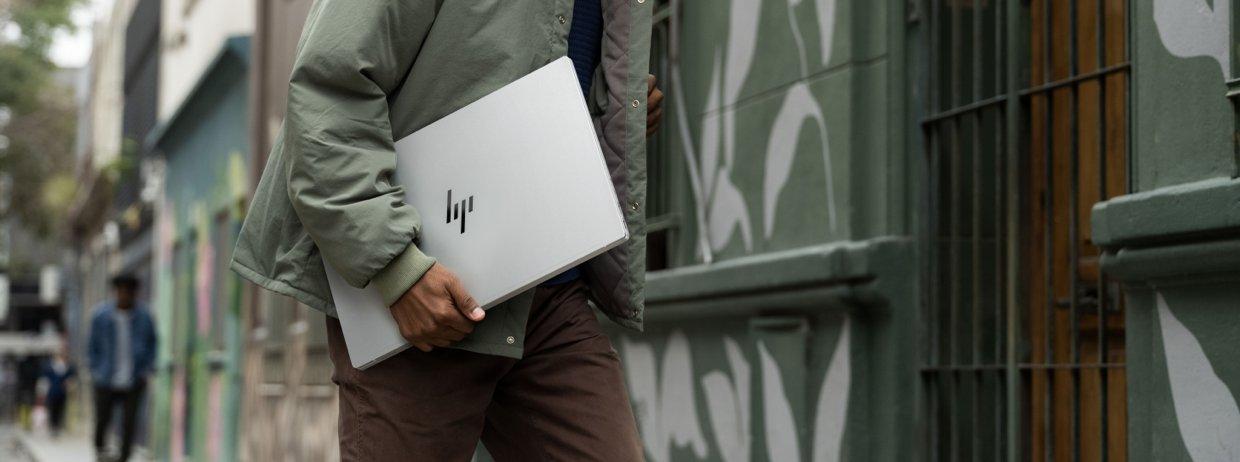 A person carrying an HP laptop down the street