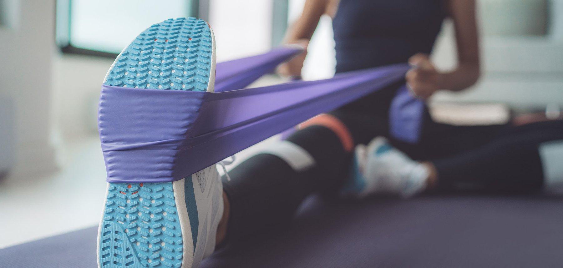 A person sitting on the floor using a resistance band