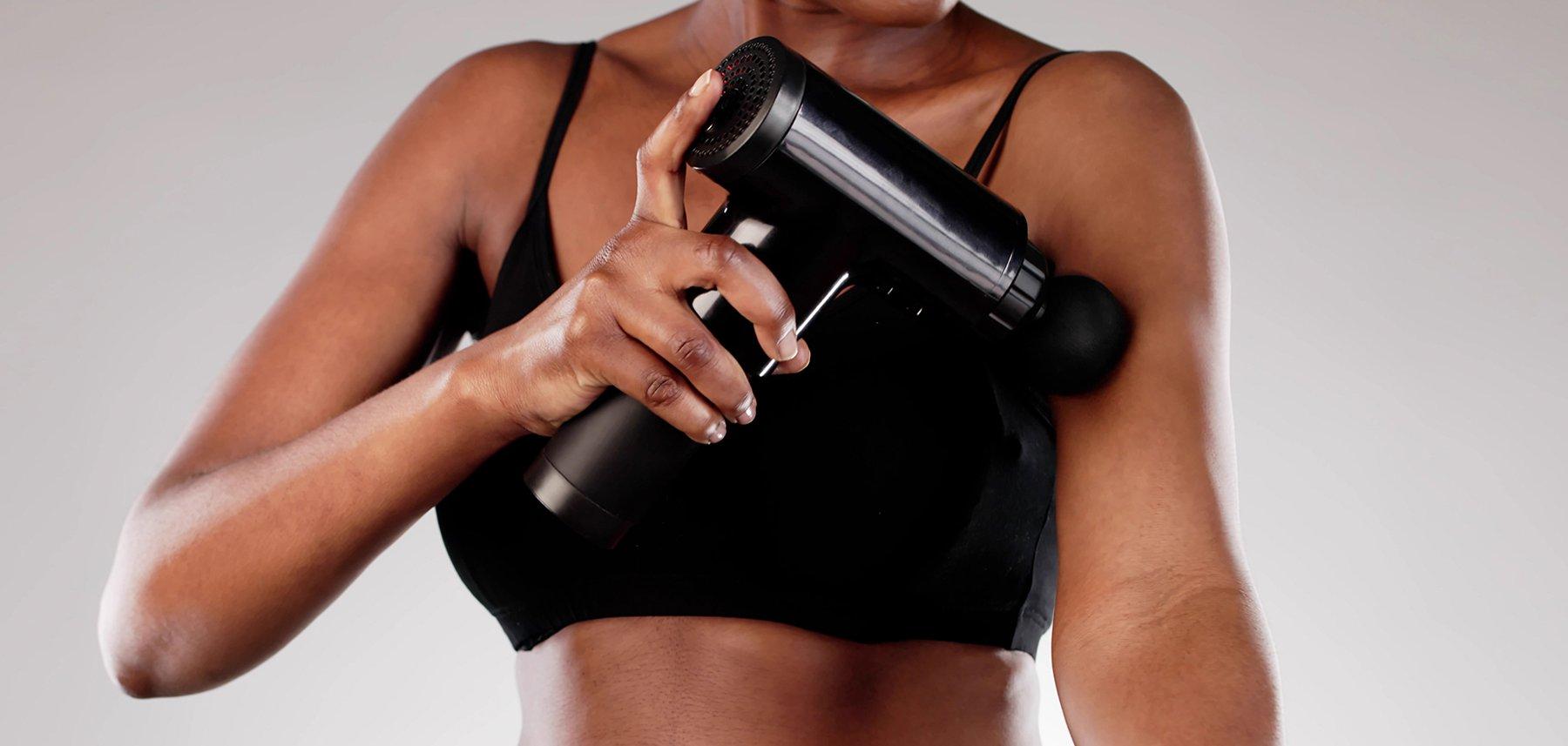 A woman using a massage gun on her arm