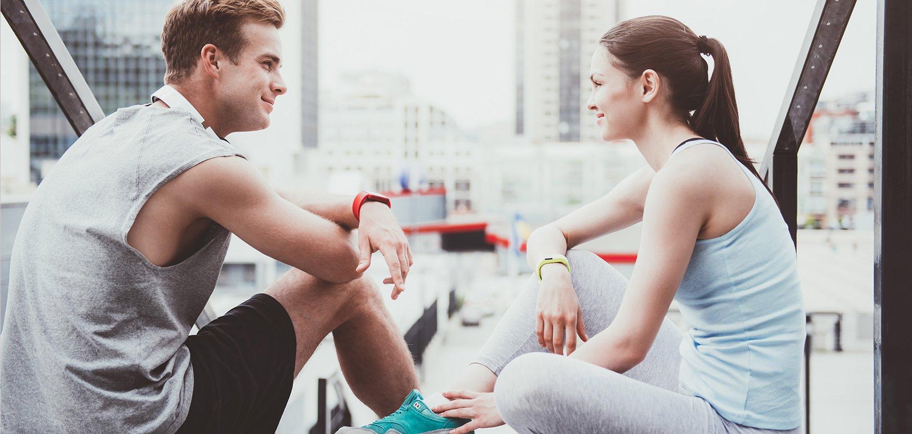 A man and woman sitting outside wearing sportswear