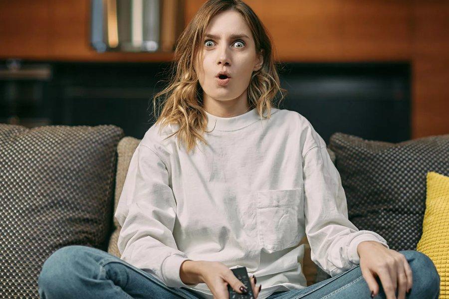 A woman sitting on a sofa looking shocked